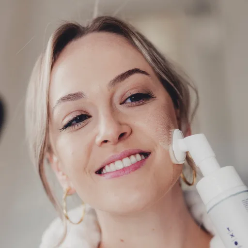 Mulher fazendo a limpeza do rosto com escova e espuma